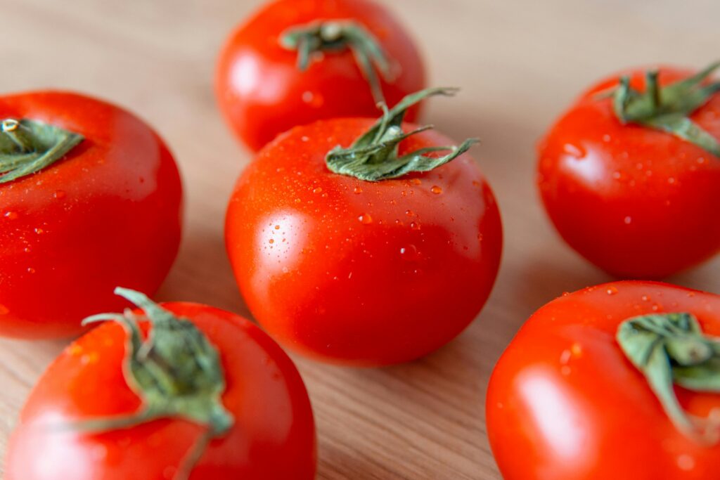 Close-up of fresh cherry tomatoes with dewdrops on a wooden surface, highlighting freshness and deliciousness.