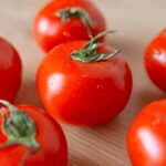 Close-up of fresh cherry tomatoes with dewdrops on a wooden surface, highlighting freshness and deliciousness.