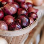 Basket of fresh red onions on a wooden stall, perfect for market or farm stock photos.