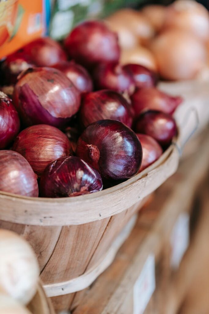 Basket of fresh red onions on a wooden stall, perfect for market or farm stock photos.